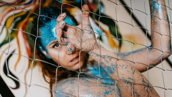 Брюнетка за сетью. Портрет женщины с синими блестками на лице — стоковое фото