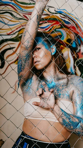 Chica morena detrás de la red. Retrato de mujer con destellos azules en la cara —  Fotos de Stock