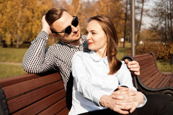 Feliz pareja sonriente en el banco del parque en otoño — Foto de Stock