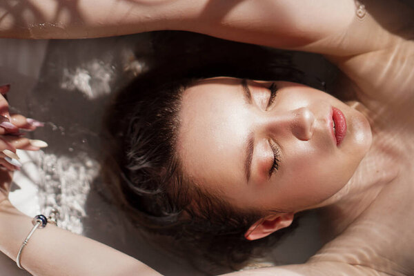 An Attractive girl relaxing in bath on light background