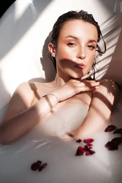 Ein attraktives Mädchen entspannt sich in der Badewanne auf hellem Hintergrund — Stockfoto