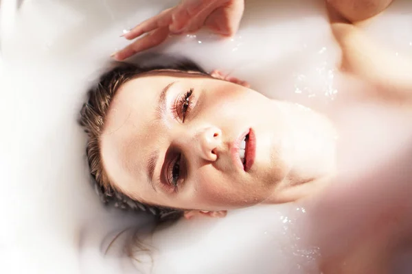 Attraktiv flicka i bad med mjölk. Spa-behandlingar för hudföryngring. — Stockfoto