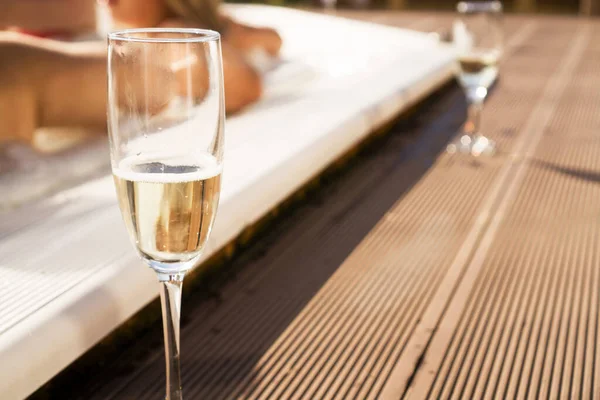 A glass of champagne by the pool on a sunny day. Blurred background — Stock Photo, Image