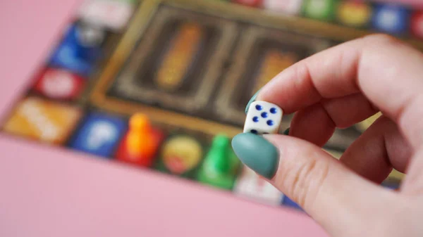 Hand wirft die Würfel auf den Hintergrund von bunten verschwommenen Brettspielen — Stockfoto