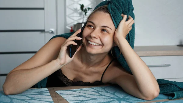Egy fiatal nő a konyhában. Telefonon beszél és mosolyog. — Stock Fotó