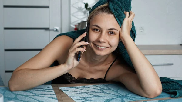 Egy fiatal nő a konyhában. Telefonon beszél és mosolyog. — Stock Fotó