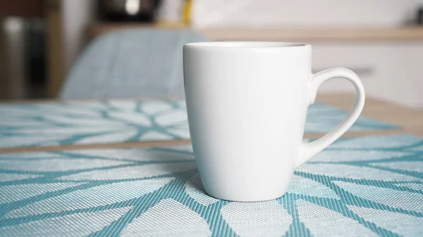 Schone witte mok met handvat staat op blauwe tafel — Stockfoto