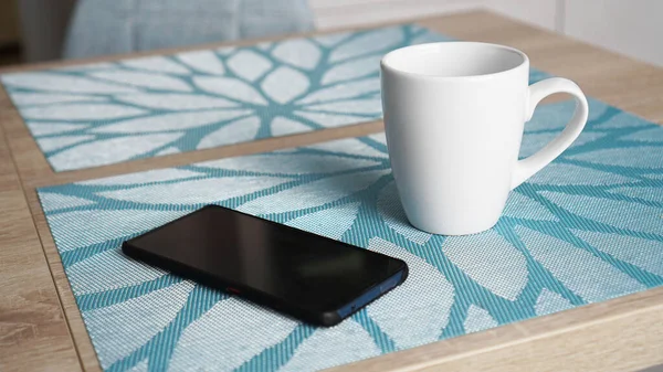 Taza blanca limpia y teléfono inteligente en la mesa —  Fotos de Stock