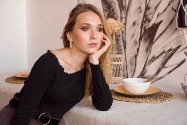 Evdeki mutfakta oturan üzgün, yalnız genç kadın..