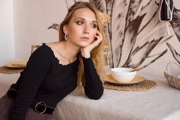 Evdeki mutfakta oturan üzgün, yalnız genç kadın..