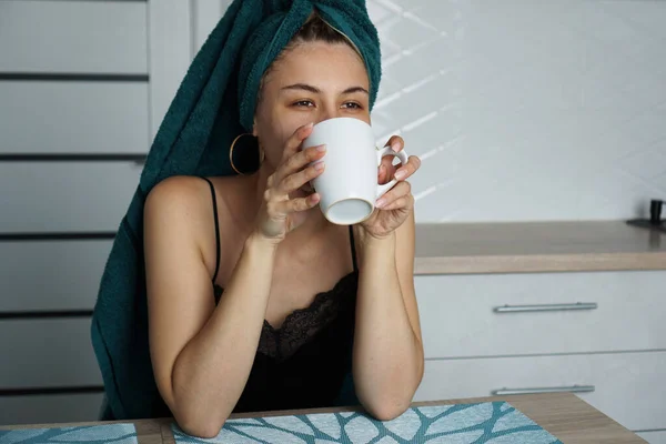 Mulher bonita senta-se na cozinha com uma xícara de café — Fotografia de Stock