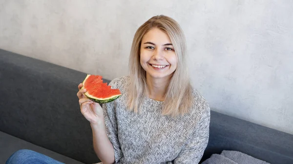 Молодая привлекательная женщина ест арбуз. Женщина смотрит в камеру и улыбается — стоковое фото