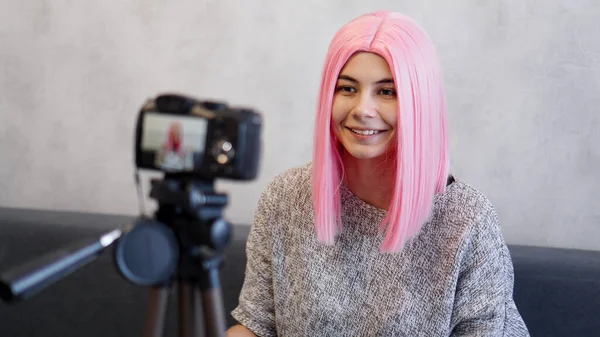 Felice blogger in parrucca rosa davanti alla telecamera su un treppiede — Foto Stock