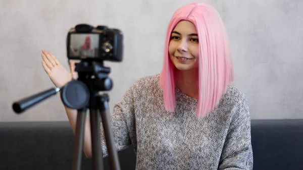 Felice ragazza blogger in parrucca rosa davanti alla telecamera su un treppiede — Foto Stock