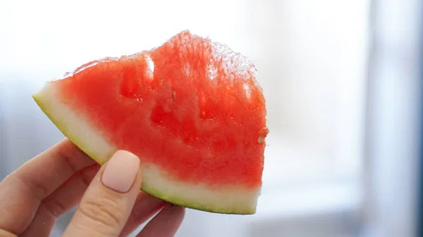 Scheibe Wassermelone in der Hand auf verschwommenem Hintergrund — Stockfoto