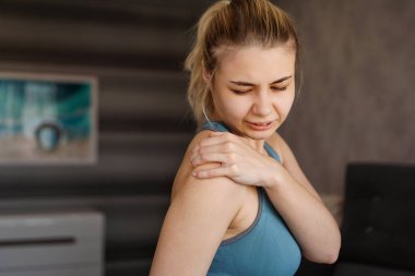 Spor kıyafeti giyen kadınlar egzersiz yaptıktan sonra omuz ağrısı hissediyorlar.