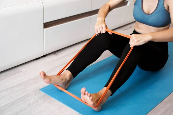 Young woman with elastic band. She trains her legs at home — Stock Photo, Image