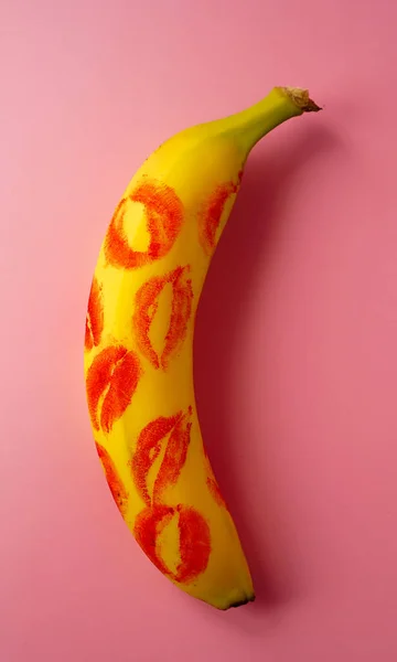 Piros rúzs egy sárga banán rózsaszín háttér. — Stock Fotó