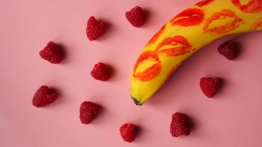 Kırmızı ruj sarı muz üzerinde pembe arka planda muzlu ahududu.