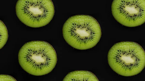 Linhas de frutas kiwi suculentas em um fundo preto, vista superior, espaço de cópia — Fotografia de Stock