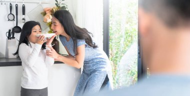 Mutlu Asyalı bir aile annesi ve güzel bir kız baba için mutfakta birlikte yemek pişiriyorlar.