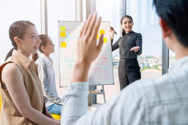 Zeki Asyalı iş kadını liderleri modern ıssız ofisteki takım arkadaşlarıyla gündelik bir toplantıda satış stratejisi ve verileri sunuyorlar ya da bir proje hedef çizelgesi için tahminlerde bulunuyorlar.