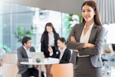 Asyalı iş adamlarının özgüvenli ve neşeli portresi iş ekibiyle buluşuyor beyin fırtınası laptoplu ve kağıt dökümanlı modern ofis geçmişi