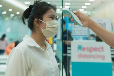 Dijital medikal elektronik termometre kullanan yeni normal koruma, Asyalı kadın müşteri korumasını ölçüyor. Mağazalarda koronavirüs hastalıklarının yayılmasını önlüyor.