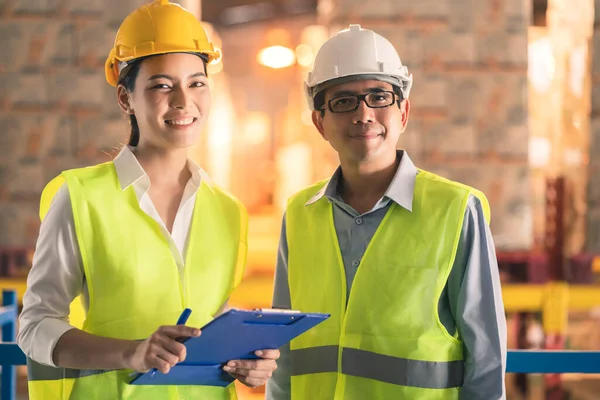 Asyalı mühendis portresi depoda çalışan mühendis müfettiş envanteriyle tartışıyor.