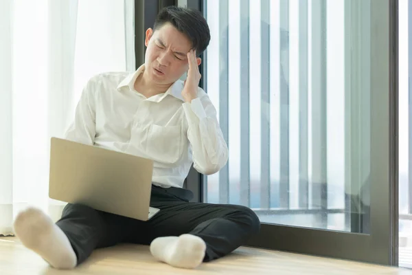 Serious asian male millennial businessman thinking cogitating about business issues. Frustrated boring  searching problem solution sitting alone on floor white work frome home quarantine coronavirus