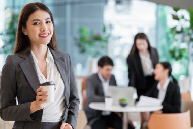Asyalı iş adamlarının özgüvenli ve neşeli portresi iş ekibiyle buluşuyor beyin fırtınası laptoplu ve kağıt dökümanlı modern ofis geçmişi