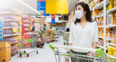 Covid salgından sonra yeni normal genç zeki Asyalı kadın süpermarkette yüz temizleme ya da maske korumalı yeni meyve sebzesi ve yeni normal yaşam tarzı seçiyor.