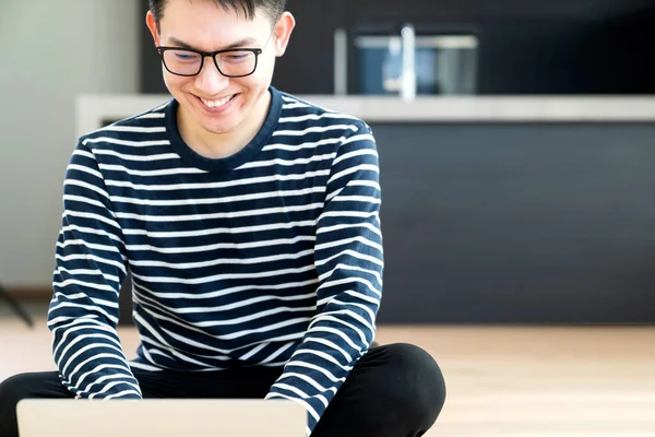 happiness peaceful smile asian male enjoy work from home quarantine  relax and positive work with laptop,asian male attractive smart freelance lay down use laptop on laminate wooden floor