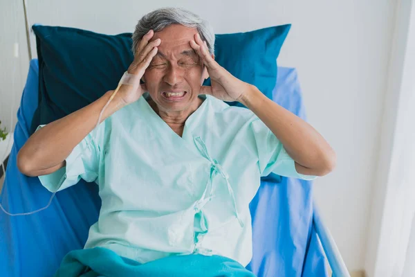 stress and headache  old senior asian grandfather in patient uniform suffer from body problem  health ideas concept