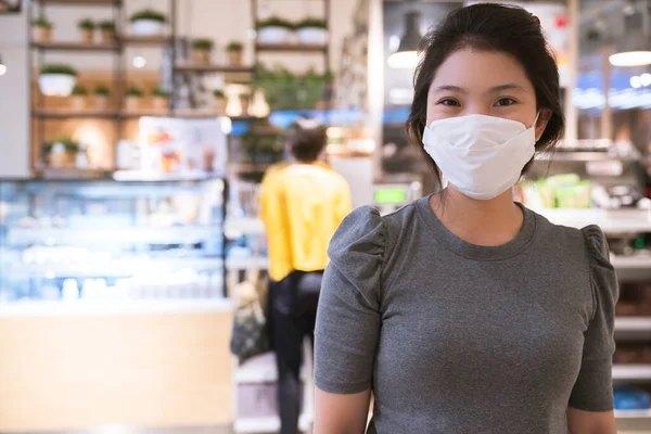 new normal after covid epidemic  young business asian female wear facial protection mask walking in center square department store mall new lifestyle after spread of corona virus covid-19