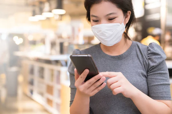 아시아인 보호용 마스크를 새로운 방식을 추상적으로 스마트폰 통화를 백화점에서 — 스톡 사진