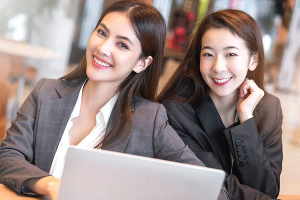 pretty asian female office staff work and smile together happy cheerful employees chatting discussing good relations modern interior office background