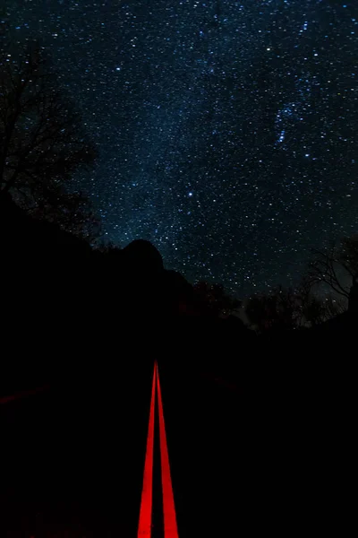 Stars glow over the January night sky in Zions National Park with Floor of the Valley road below.