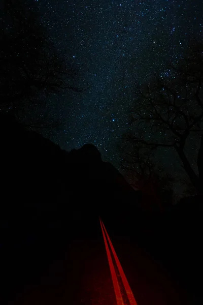 Stars glow over the January night sky in Zions National Park with Floor of the Valley road below.