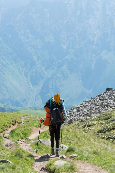 Kazbegi, Gürcistan - Gergeti Trinity Kilisesi 'nden Gergeti Buzulu' na kadar dağ yolunda yürüyüş yapan bir yürüyüşçü. Kazbegi, Mtskheta-Mtianeti, Georgia 'da ünlü bir manzara..