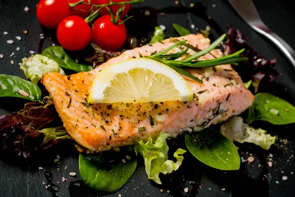 Grilled salmon fillet with salad on black slate plate — Stock Photo, Image