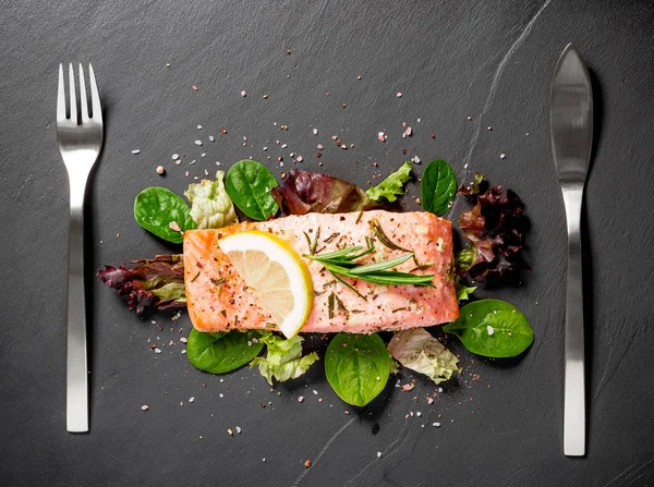 Grilled salmon fillet with salad on black slate plate — Stock Photo, Image