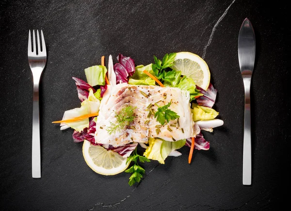 Filete de bacalao a la parrilla con ensalada en plato de pizarra negra — Foto de Stock