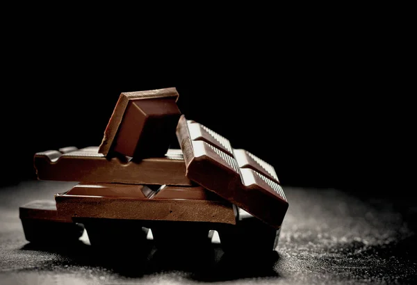 Треснувший темный шоколад на черном фоне — стоковое фото