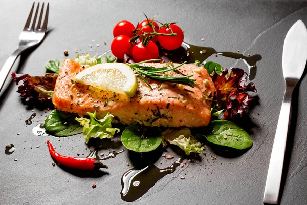 Grilled salmon fillet with salad on black — Stock Photo, Image