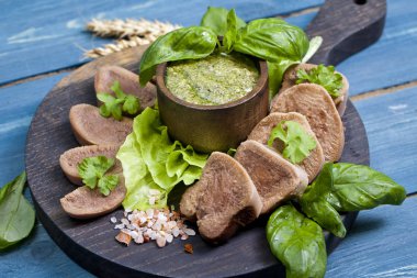 Pesto ve salata ile koyu ahşap tabloda haşlanmış Dana dil