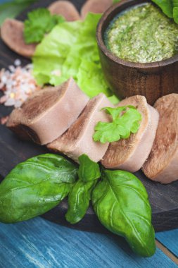Pesto ve salata ile koyu ahşap tabloda haşlanmış Dana dil