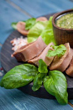 Pesto ve salata ile koyu ahşap tabloda haşlanmış Dana dil