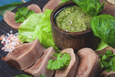 Pesto ve salata ile koyu ahşap tabloda haşlanmış Dana dil