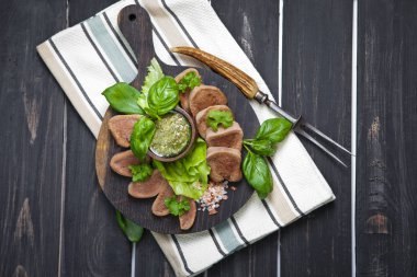 Pesto ve salata ile koyu ahşap tabloda haşlanmış Dana dil